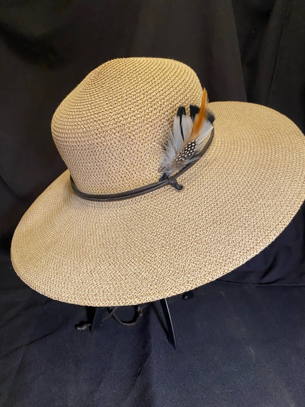 Striking straw sun hat featuring a wide brim and a decorative feather hatband.